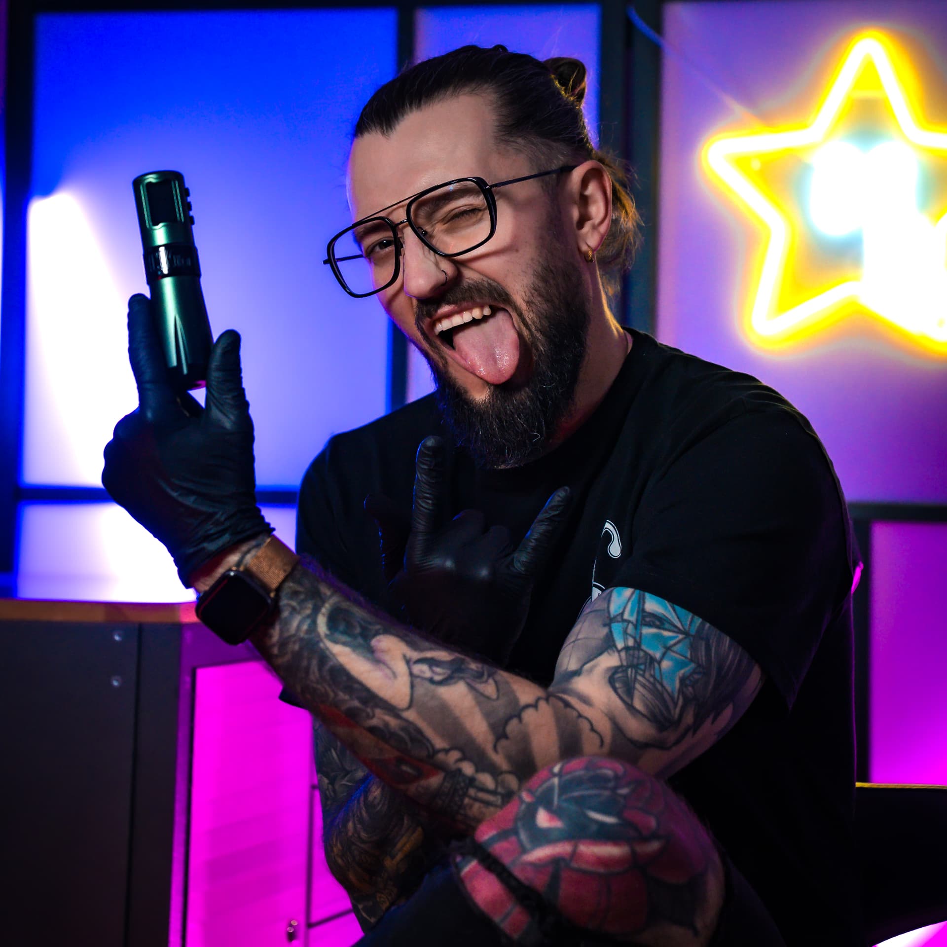 Adrian Cierpikoski z maszynką tatuażu przy neonowym tle